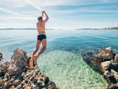 man taking a leap of faith and jumping into the ocean